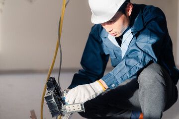 しゃがみ込んで配線器具を扱う電気工事士