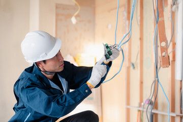 木造建築の屋内で配線作業を行う電気工事士