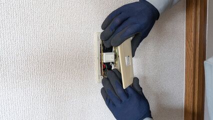壁のスイッチプレートを取り付ける手元