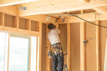 木造建築の屋内で配線作業を行う作業員
