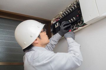 分電盤の配線を修理点検する電気工事士